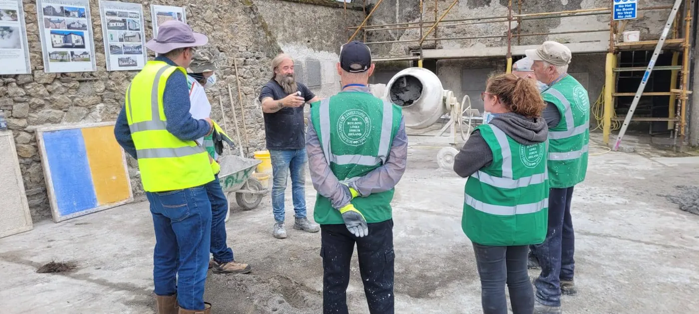 A group in high-visibility vests at a hands-on lime workshop